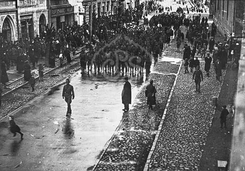 30. pěší pluk při pochodu po Hlavnej ulici v Prešově. Vojáci pochodují směrem od Košic, od železniční stanice. První čtvrtina roku 1919